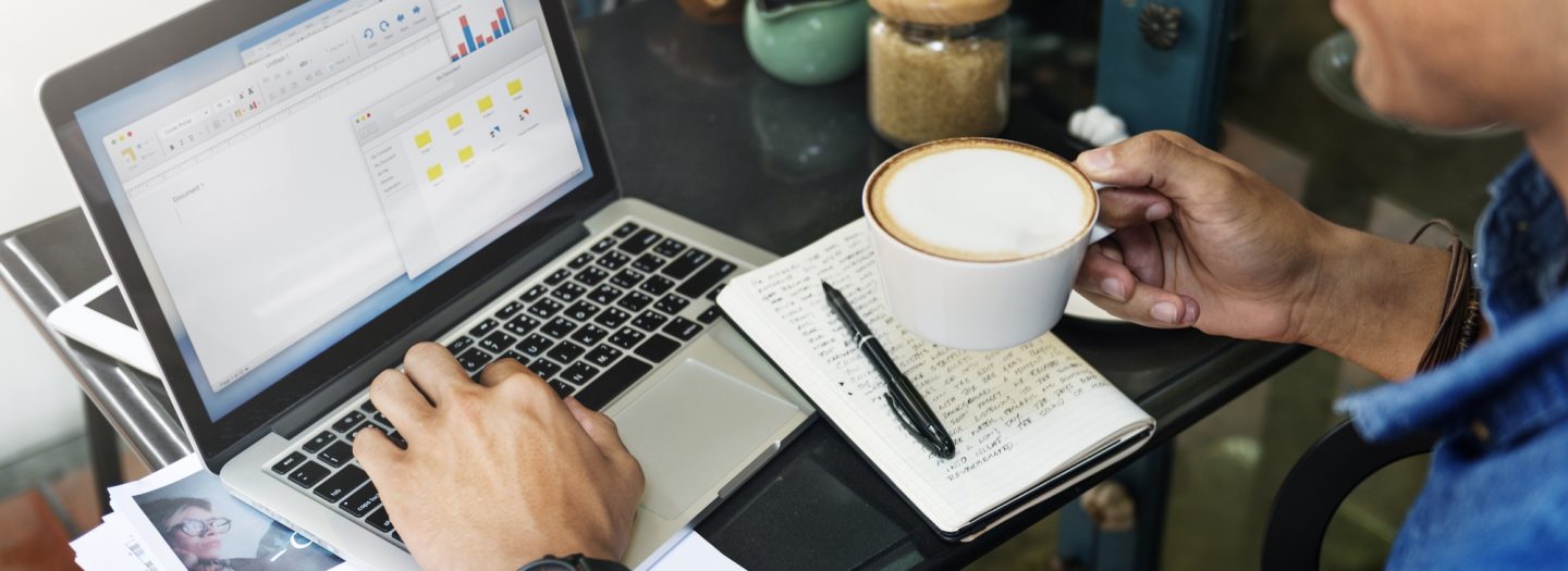 Man op de laptop met koffie in handen