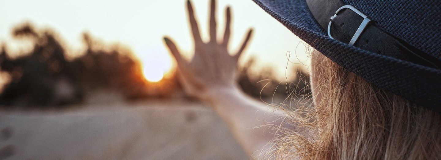 Vrouw met hand bij zonsondergang bijgesneden