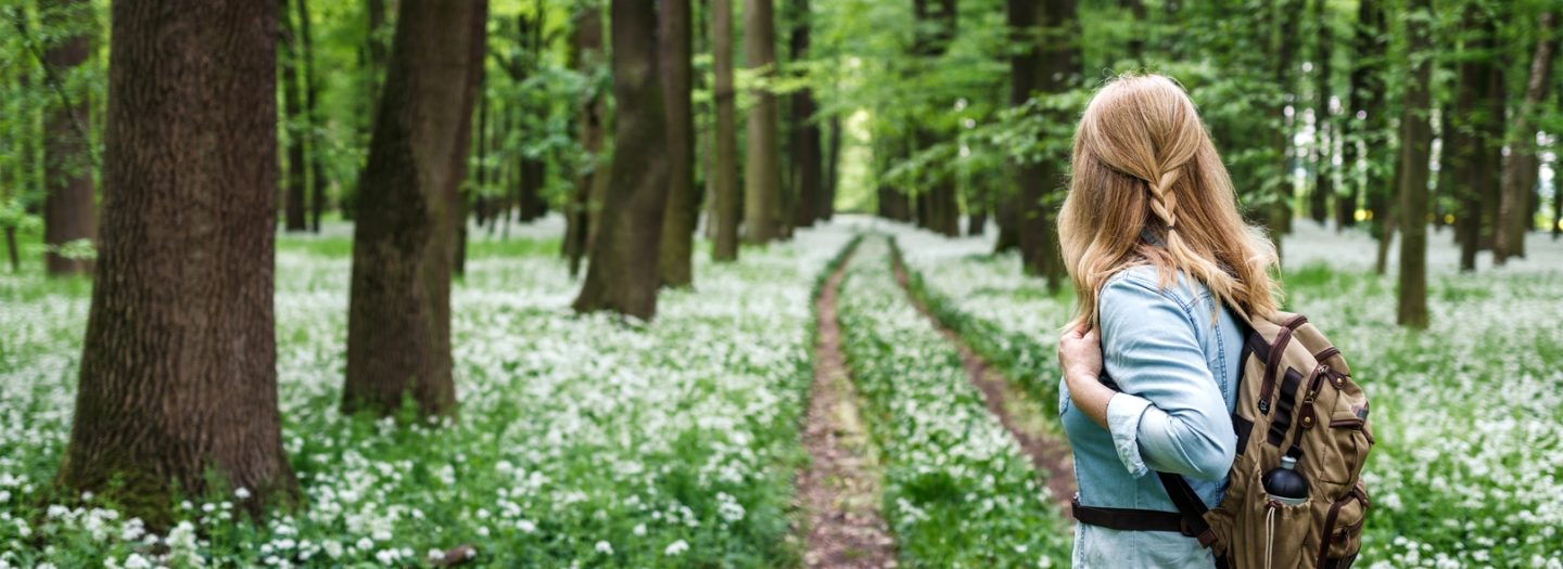 Dame met rugzak in het bos met bloemen