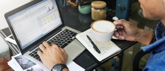 Man op de laptop met koffie in handen