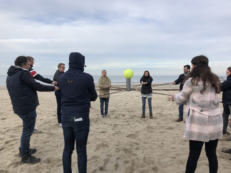 Groep op het strand met grote tennisbal